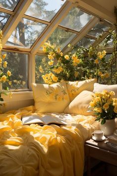 a sun room with yellow flowers in the window and pillows on the bed, next to a coffee table