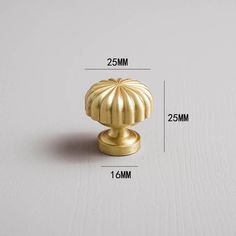 an image of a golden knob on a white surface with measurements for the top and bottom