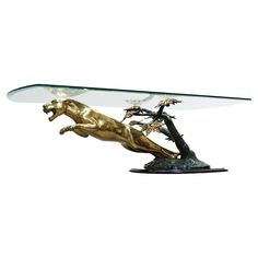 a glass topped table with a gold horse and tree on the top, against a white background