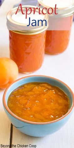 homemade apricot jam in a blue bowl next to two oranges on a white table