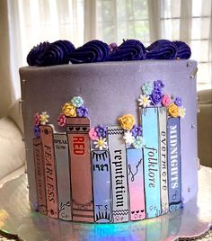 a cake decorated with books and flowers on a table in front of a curtained window