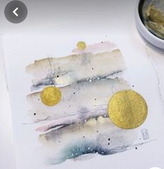 a close up of a piece of paper with gold circles on it and a paintbrush