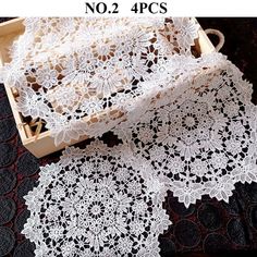 two pieces of white crocheted doily in a wooden box on a black surface