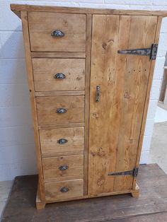 an old wooden cabinet with metal handles on it's doors and drawers, sitting against a white brick wall