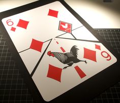 a close up of a playing card with a rooster on the front and red squares on the back