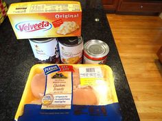 some food is sitting on top of a counter next to cans of soup and other items