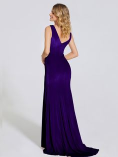 a woman in a long purple dress looking back at the camera with her hand on her hip