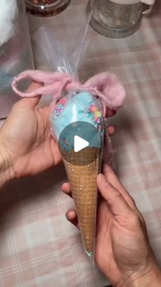 someone is holding an ice cream cone in their hand with pink decorations on it and the cones are wrapped in cellophane