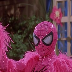 the pink spider man is dressed in bright pink furs and has his arms spread out