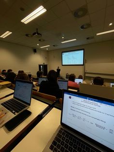 two laptop computers sitting on top of a table in front of a class room full of people