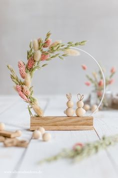 an arrangement of small wooden beads and flowers on a white table with other items around it