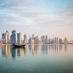 a small boat floating on top of a large body of water next to tall buildings