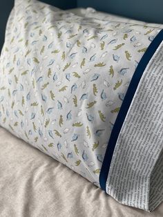 a pillow with blue and green designs on it sitting on a bed next to a wall