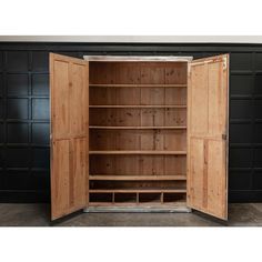 an open wooden cabinet with two doors and shelves on the side, in front of a black wall