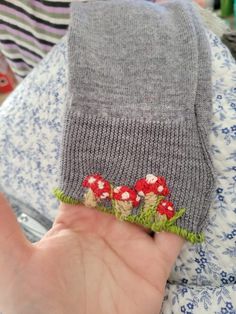 a hand is holding a pair of socks with flowers on them and green grass in the middle