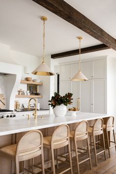 an instagram photo of a kitchen with white countertops and gold pendant lights hanging from the ceiling