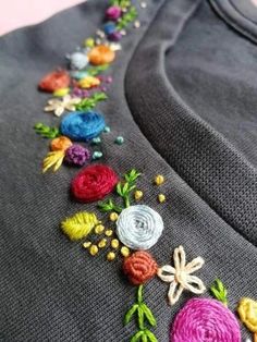 a close up of a shirt with flowers on the front and side, embroidered onto it