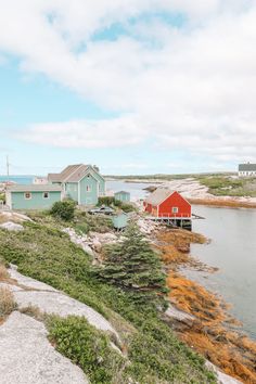 some houses are on the shore by the water and grass in front of them is a red house