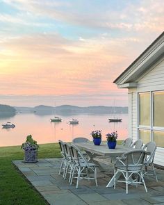 a table and chairs on a patio overlooking the water with boats in the lake behind it