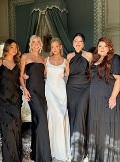 four women in black and white gowns posing for a photo with one woman wearing a dress