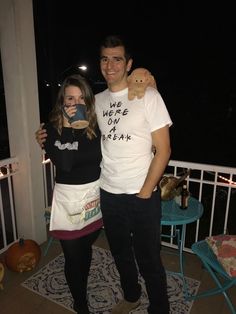 a man standing next to a woman on top of a balcony holding a teddy bear