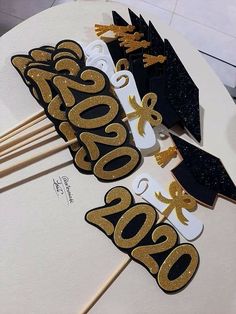 gold and black graduation decorations on top of a white round table with chopsticks