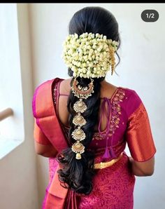 a woman with flowers in her hair wearing a pink saree and gold jewelry on her head