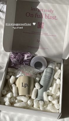 an open box with some items in it on a white sheeted surface, next to a bottle of lotion