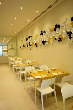 a long table with yellow and white plates on the wall next to it is set for dinner