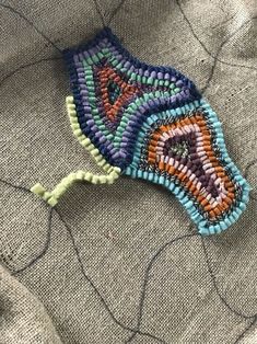 a piece of beaded fabric with an orange, blue and green design on it