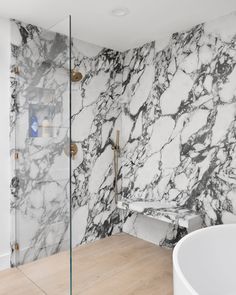 a bathroom with marble walls and flooring in the shower area, along with a bathtub