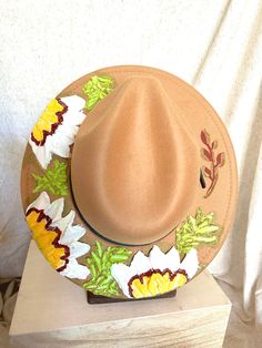 This one of a kind, hand painted, textured floral fedora is the perfect walking art piece. Each hat is uniquely crafted and perfect for any occasion.  This tan fedora is crafted with white, yellow, deep red flowers, and bright green leaves with metallic gold accents. These island treasures are shipped straight to you from the Hawaiian island of Oahu. (Hats are water resistant. Keep out of heavy rain. Spot clean only) Artisan Wide Brim Fedora For Spring, Whimsical Wide Brim Handmade Fedora, Whimsical Handmade Wide Brim Fedora, Handmade Whimsical Wide Brim Fedora, Artisan Felt Hat For Summer Rodeo, Bohemian Felt Hat For Beach Spring, Bohemian Felt Hat For Beach In Spring, Country Style Felt Hat For Beach In Spring, Spring Bohemian Felt Hat For The Beach