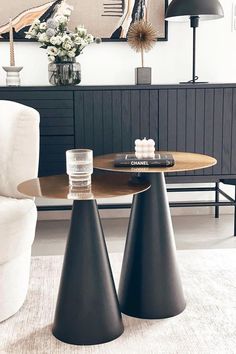 two black vases sitting on top of a wooden table next to a white couch