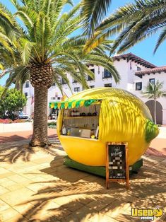 a large yellow food cart sitting next to a palm tree