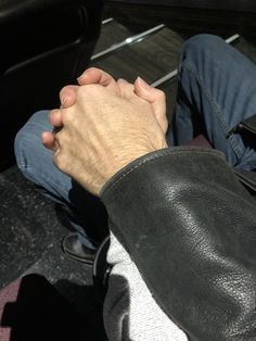 two people holding hands while sitting in the back of a car