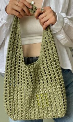 a woman holding a green crocheted purse