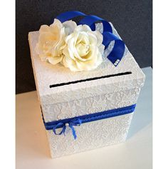 a white box with blue ribbon and flowers in it