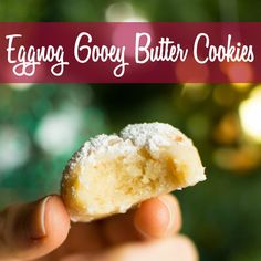 a hand holding a half eaten sugary butter cookie in front of a christmas tree