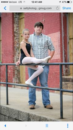 a man standing next to a woman on top of a metal rail in front of a red brick building