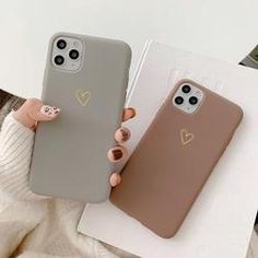 two phone cases with heart stickers on them, one is grey and the other is brown