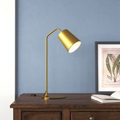 a desk lamp sitting on top of a wooden table next to a framed photo and book