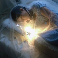 a woman laying on top of a bed next to a star shaped light in her hand