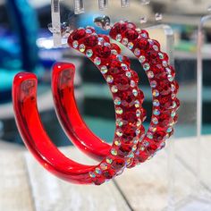 Crafted from high-quality translucent red acrylic lucite, these hoops feature a sleek and modern design that is sure to turn heads. The hoops have a diameter of 2 inches, making them a bold and impactful accessory. To enhance their allure, we have adorned these earrings with dazzling red and iridescent (ab) rhinestones. The vibrant and shimmering stones add a pop of color and sparkle to the black background, creating a captivating contrast that will catch the light with every movement. Measuring 10mm in width, these hoops strike the perfect balance between elegance and statement-making style. They are lightweight and comfortable to wear, ensuring that you can dance the night away without any discomfort. These earrings are designed specifically for women who love to make a bold fashion stat Red Small Hoop Earrings For Party, Small Red Hoop Earrings For Party, Red Plastic Party Jewelry, Trendy Red Hoop Earrings For Party, Wedding Night, Jewelry Earrings Hoops, Bold Fashion, Black Background, Black Backgrounds