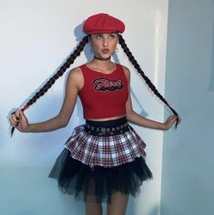 a woman in a red shirt and plaid skirt is holding a pair of scissors with her hands