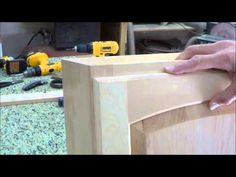 a person is working on a cabinet with tools and woodworking equipment in the background