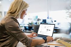 a woman sitting at a table using a laptop computer