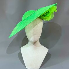 Cool lime green sinamay straw cloth saucer with a peekaboo silk flower underbrim, and accented with graceful curls of sinamay.﻿ Universally flattering, this large saucer style suits most any wearer. Headband, elastic, and comb attachment for easy, comfortable wear. Lifted Millinery headwear is constructed with time honored techniques and fine craftsmanship. All hats are meticulously blocked and sewn by hand without the use of adhesives to attach trims. This ensures a long lasting hat with the ability to be retrimmed throughout the years. A hat box for careful storage is included with every hat purchase. Please allow one week, from date of purchase, for your hat to be shipped. Elegant Green Fascinator For Church, Elegant Green Church Fascinator, Spring Church Fascinator In Sinamay, Spring Church Sinamay Fascinator, Green Mini Hats For Spring Church Occasions, Green Mini Hats For Church In Spring, Chic Sinamay Fascinator For Summer, Spring Green Fascinator For Races, Summer Sinamay Fascinator For Garden Party