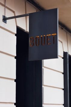 a sign hanging from the side of a building that says, boutt on it