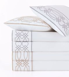 a stack of four white and gold pillows on top of each other