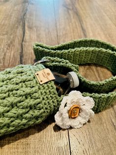 a green crocheted bag with a white flower on it